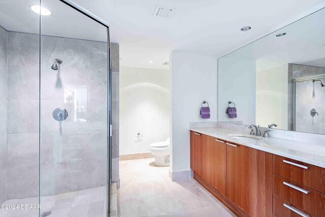 bathroom featuring toilet, vanity, and a shower with shower door