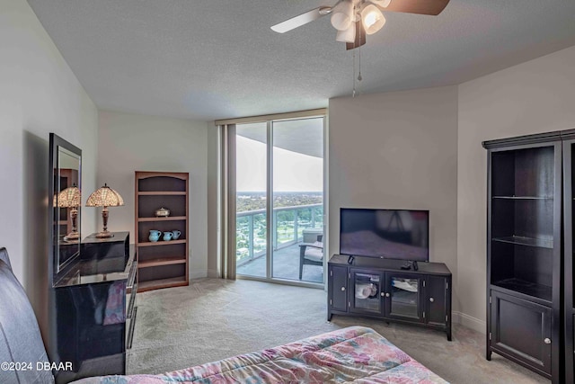 carpeted bedroom with ceiling fan, a wall of windows, a textured ceiling, and access to exterior