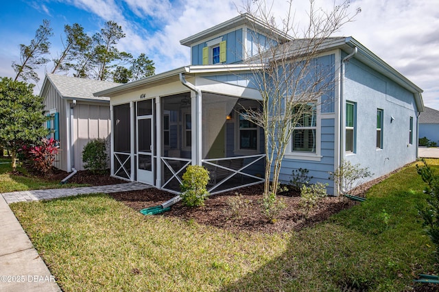 exterior space with board and batten siding, a front yard, and a sunroom