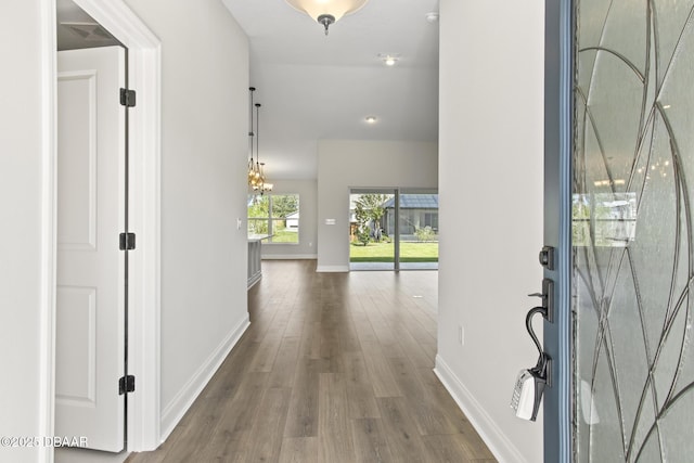 entryway featuring wood finished floors, baseboards, and a chandelier
