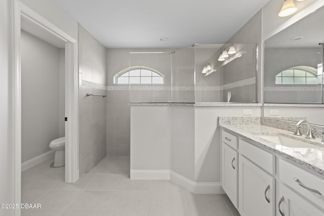 full bathroom featuring walk in shower, vanity, toilet, tile patterned flooring, and baseboards