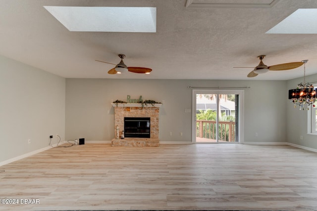 4766 S Atlantic Ave, Ponce Inlet, FL 32127 - unfurnished living room featuring light wood-style flooring, a ceiling fan, healthy amount of natural light, a stone fireplace, and a textured ceiling