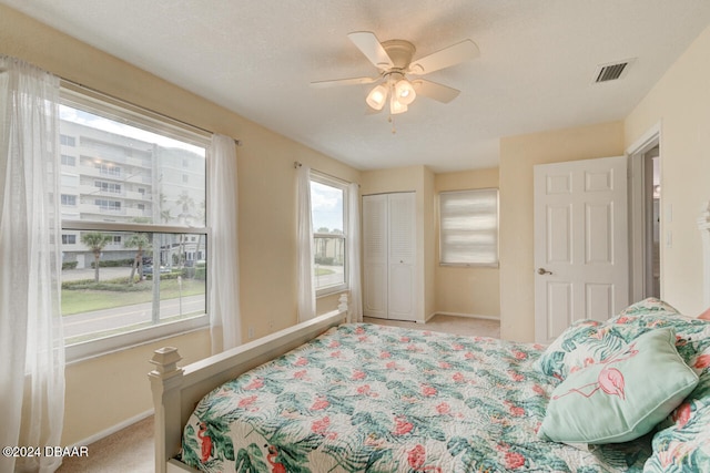 carpeted bedroom featuring ceiling fan, a closet, and a textured ceiling