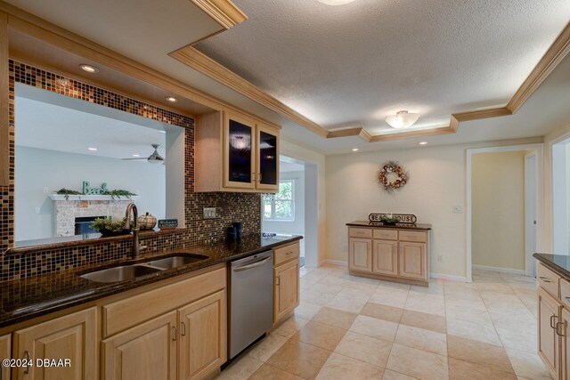 4766 S Atlantic Ave, Ponce Inlet, FL 32127 - kitchen featuring stainless steel dishwasher, a sink, a raised ceiling, decorative backsplash, and crown molding