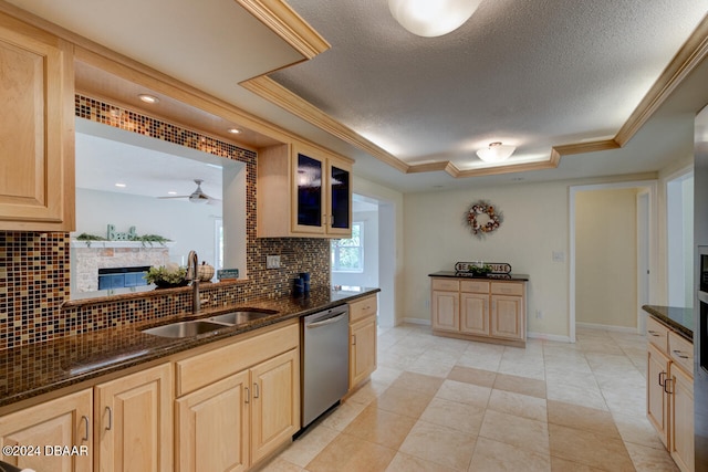 kitchen with a tray ceiling, backsplash, dishwasher, and sink