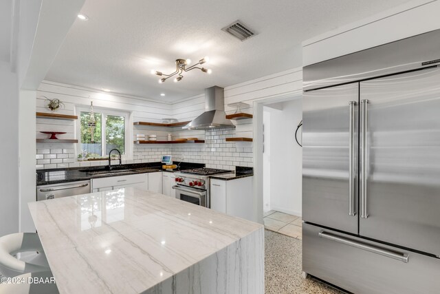 kitchen with dark stone counters, white cabinetry, backsplash, premium appliances, and sink