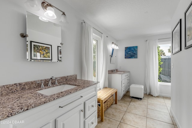 bathroom with tile patterned flooring, vanity, and a textured ceiling