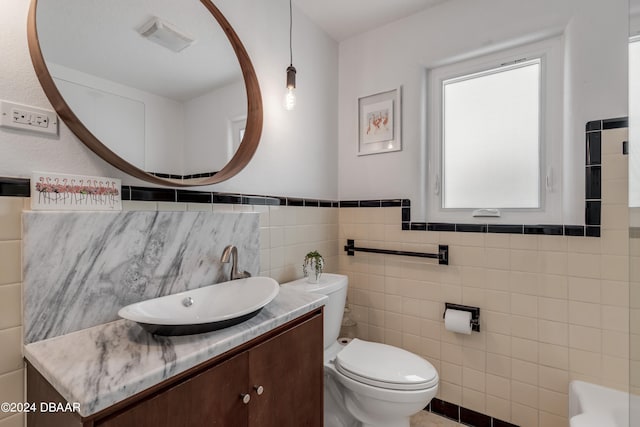 bathroom featuring tile walls, vanity, and toilet