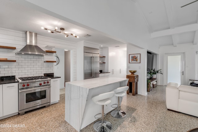 kitchen with tasteful backsplash, a kitchen island, white cabinets, wall chimney exhaust hood, and high end appliances