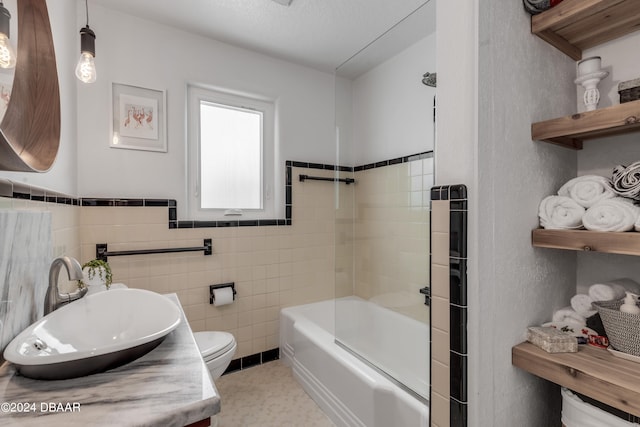 full bathroom with toilet, tile walls, tiled shower / bath, a textured ceiling, and vanity