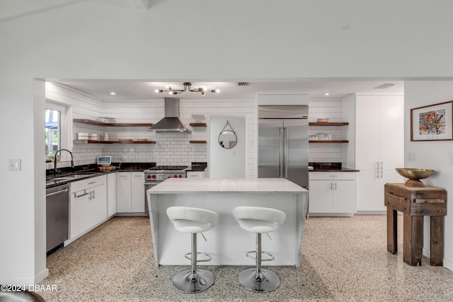 kitchen with white cabinetry, sink, wall chimney exhaust hood, a center island, and premium appliances