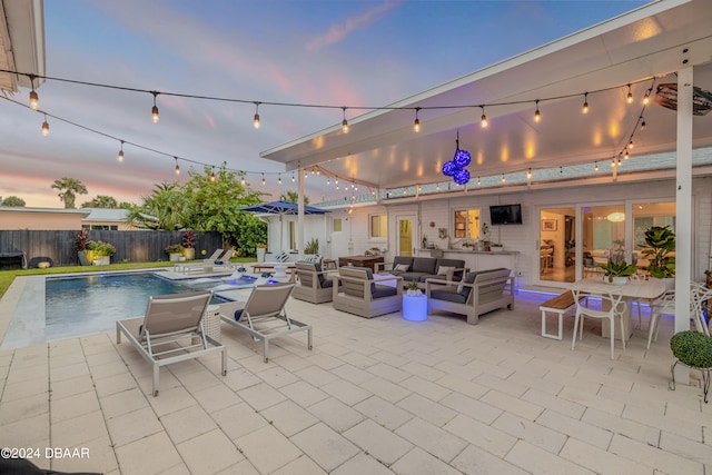 patio terrace at dusk with a fenced in pool and an outdoor living space