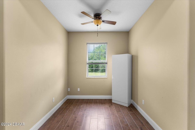 empty room featuring a textured ceiling, dark wood-type flooring, and ceiling fan