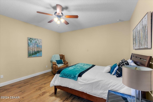 bedroom featuring hardwood / wood-style floors, ceiling fan, and a textured ceiling