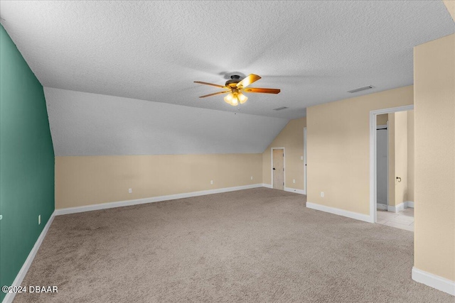 bonus room featuring a textured ceiling, lofted ceiling, light carpet, and ceiling fan