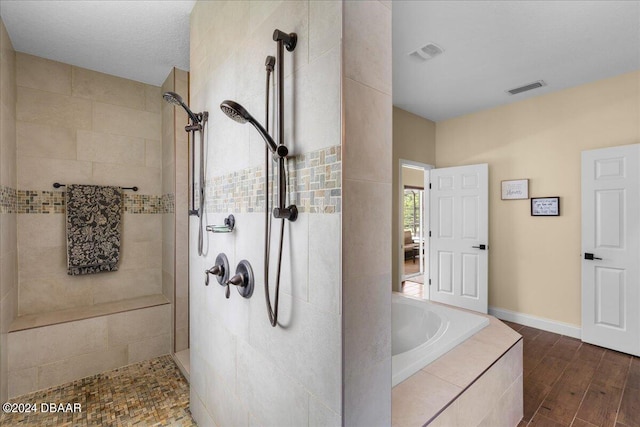 bathroom featuring hardwood / wood-style floors, a textured ceiling, and plus walk in shower