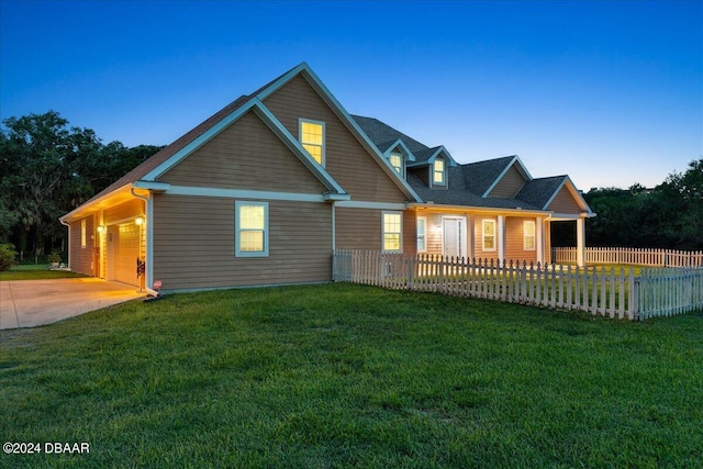 back house at dusk with a garage and a lawn