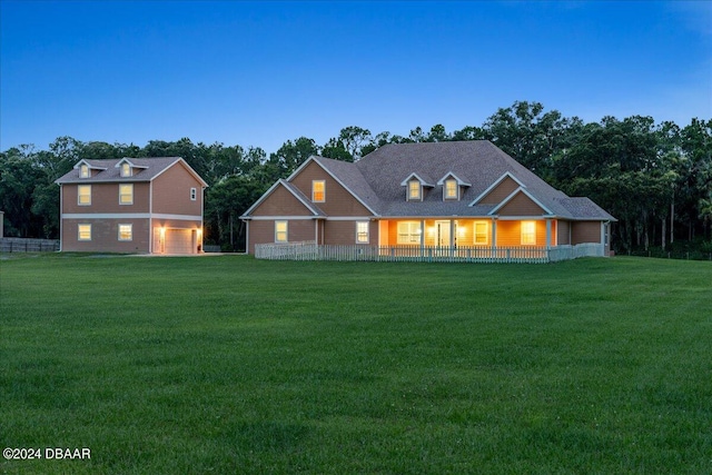 view of front of property featuring a garage, covered porch, and a yard