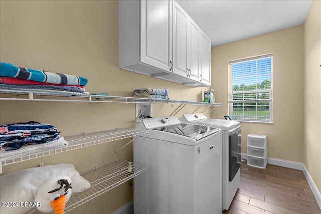 laundry area featuring cabinets, light wood-type flooring, and washer and clothes dryer