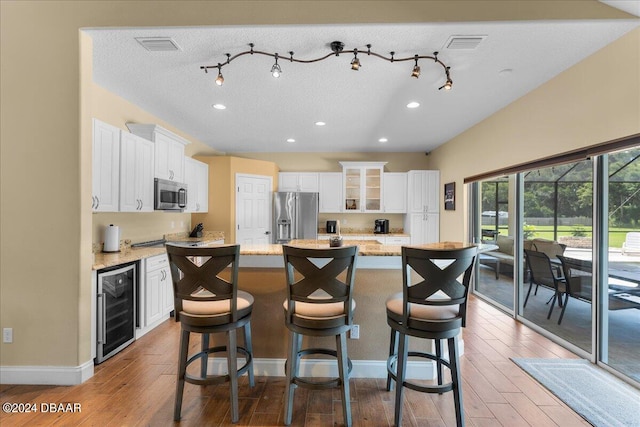 kitchen featuring light wood-type flooring, appliances with stainless steel finishes, a center island, and beverage cooler