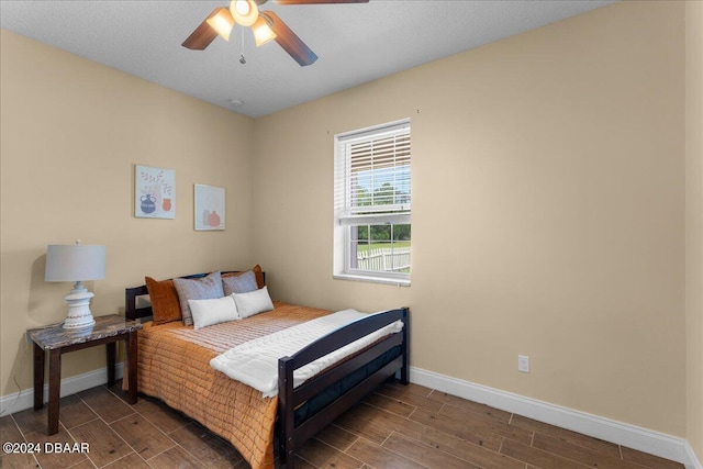 bedroom with ceiling fan, a textured ceiling, and dark hardwood / wood-style floors