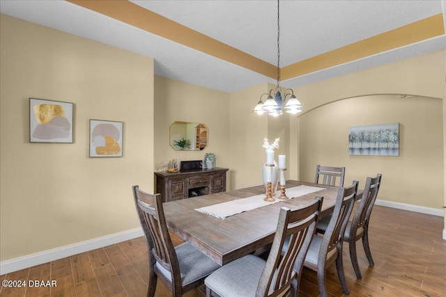 dining room with dark wood-type flooring, a textured ceiling, and an inviting chandelier