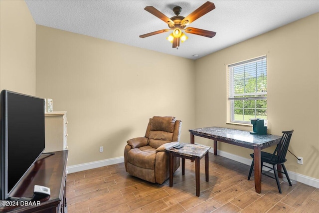 interior space with a textured ceiling, ceiling fan, and light hardwood / wood-style flooring