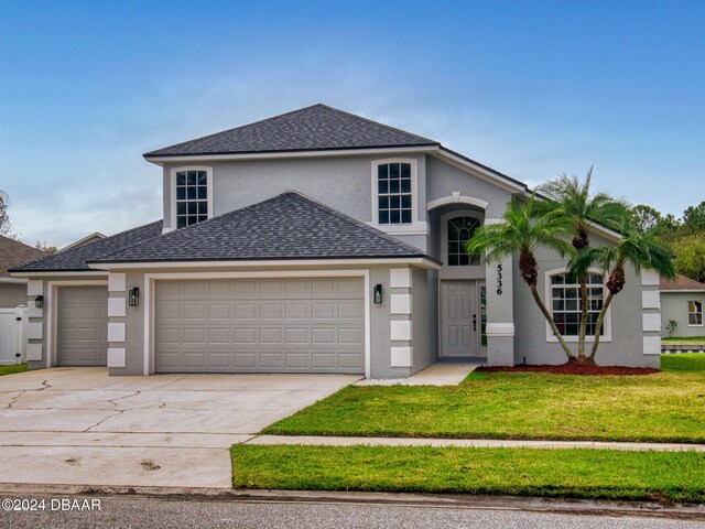 5336 Georgia Peach Ave, Port Orange, FL 32128 - view of front of home with a garage, concrete driveway, roof with shingles, a front yard, and stucco siding