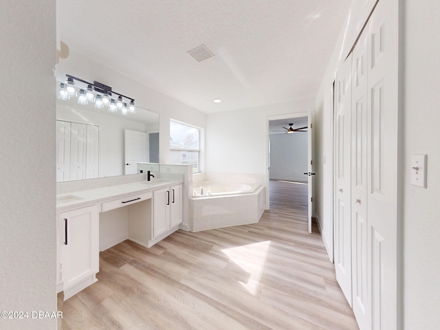 5336 Georgia Peach Ave, Port Orange, FL 32128 - bathroom with double vanity, a garden tub, wood finished floors, and a ceiling fan