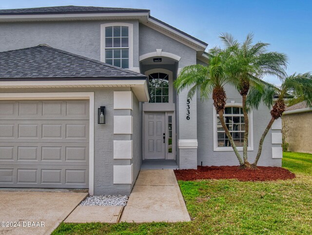 5336 Georgia Peach Ave, Port Orange, FL 32128 - doorway to property featuring an attached garage and stucco siding
