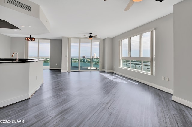 unfurnished living room with visible vents, baseboards, dark wood finished floors, and ceiling fan with notable chandelier