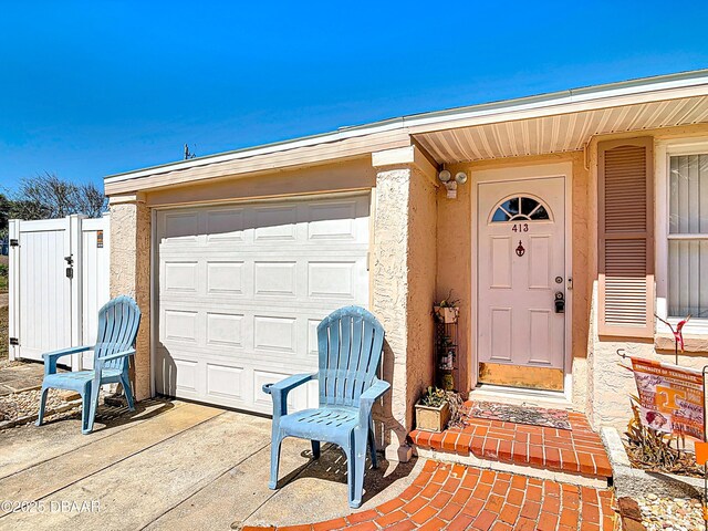 413 Frances Ter, Daytona Beach, FL 32118 - doorway to property featuring stucco siding, driveway, and a garage