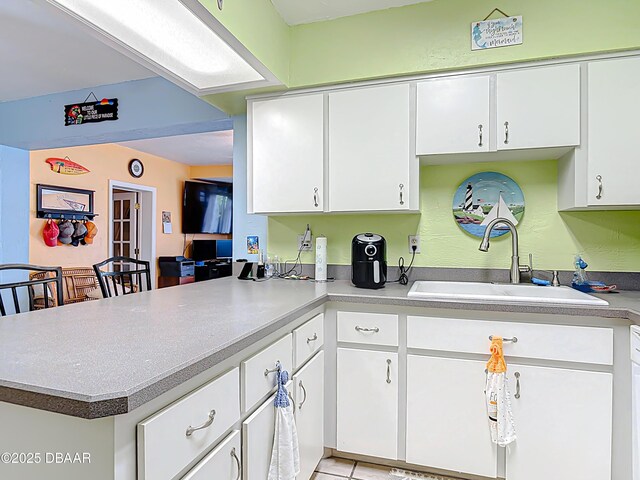 413 Frances Ter, Daytona Beach, FL 32118 - kitchen featuring a peninsula, white cabinetry, light countertops, and light tile patterned flooring