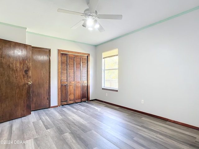 unfurnished bedroom featuring ceiling fan, two closets, ornamental molding, and light hardwood / wood-style flooring