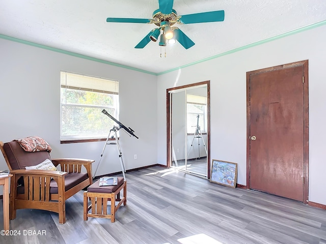 sitting room featuring ceiling fan, light wood-type flooring, and ornamental molding