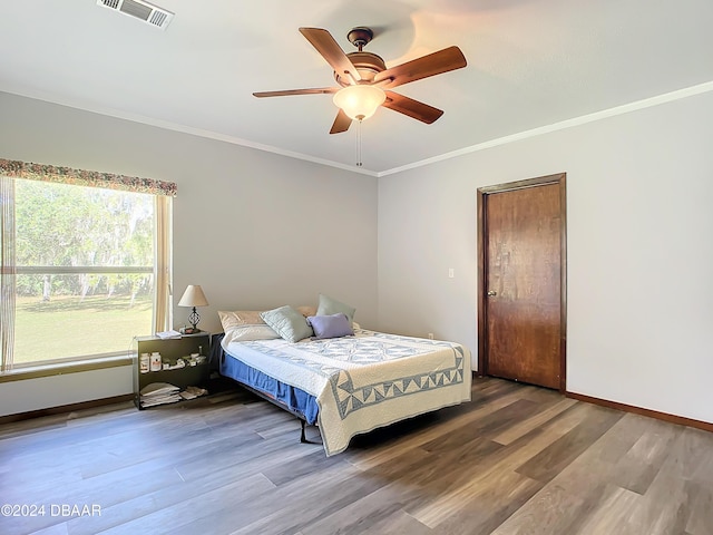 bedroom with hardwood / wood-style floors, ceiling fan, and crown molding