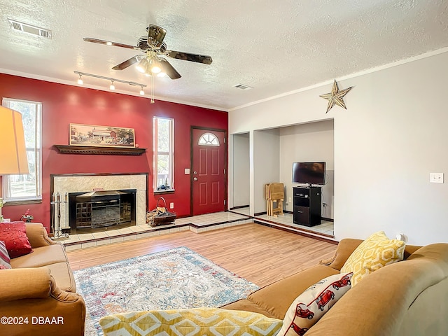 living room featuring crown molding, hardwood / wood-style floors, ceiling fan, and a textured ceiling