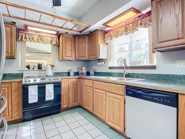 kitchen with dishwasher, black range, light tile patterned floors, and sink