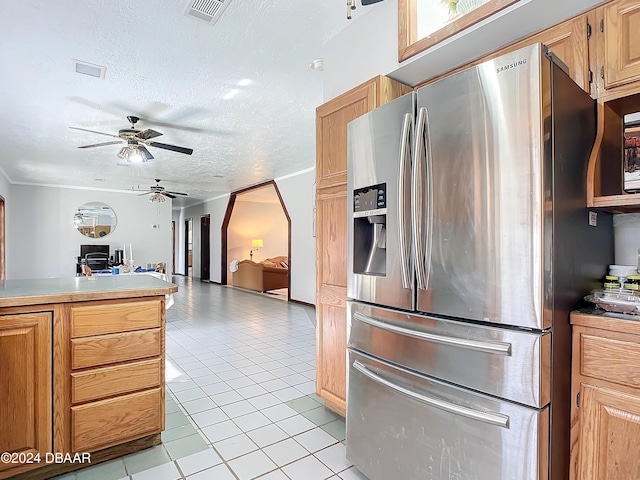 kitchen with ceiling fan, stainless steel refrigerator with ice dispenser, a textured ceiling, light brown cabinetry, and light tile patterned flooring