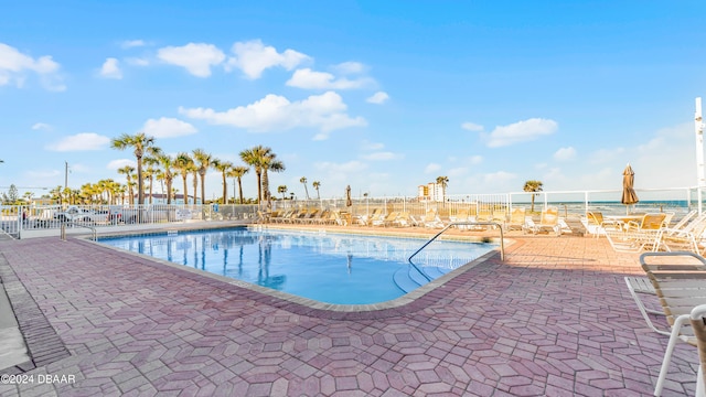 view of pool featuring a water view and a patio