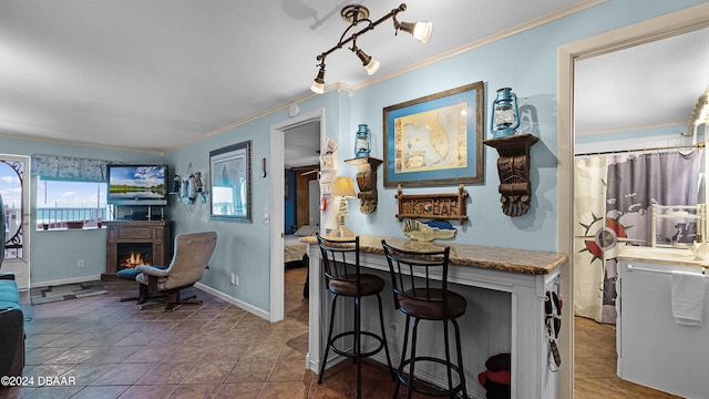 kitchen with a breakfast bar area, crown molding, and tile patterned flooring