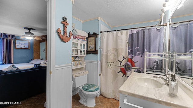 bathroom featuring ceiling fan, a textured ceiling, toilet, vanity, and ornamental molding