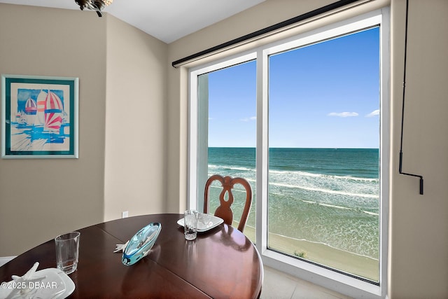 tiled dining room with a view of the beach and a water view