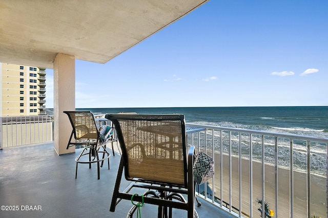 balcony with a beach view, a water view, and radiator heating unit