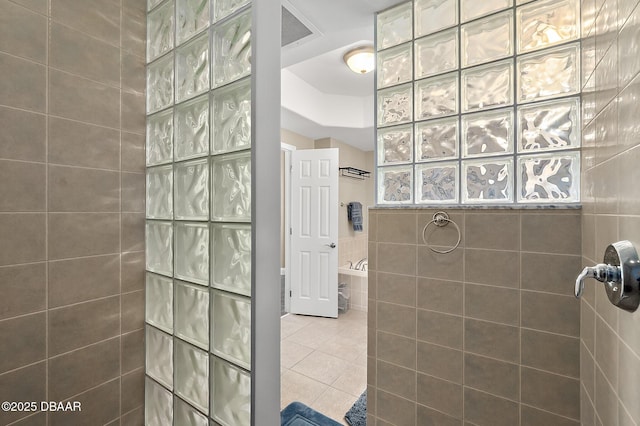 bathroom featuring tile patterned flooring and a tile shower