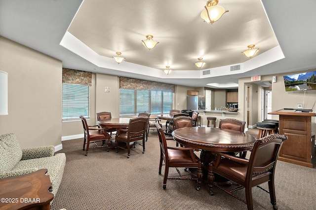 carpeted dining room with a tray ceiling