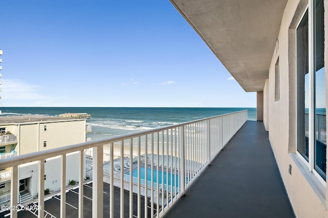 balcony featuring a view of the beach and a water view