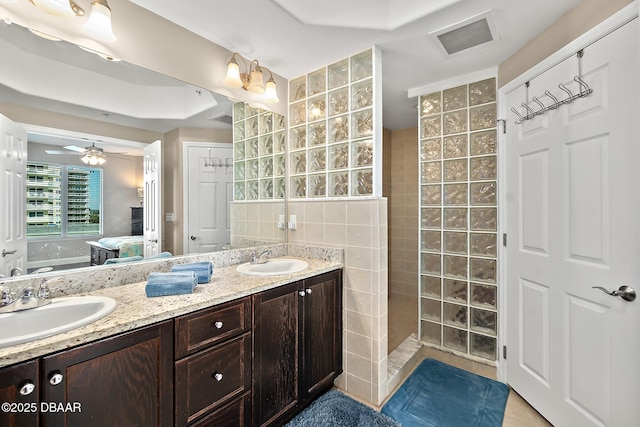 bathroom with a tile shower, vanity, tile walls, and ceiling fan