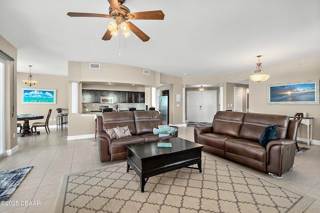 living room with ceiling fan with notable chandelier and light tile patterned floors