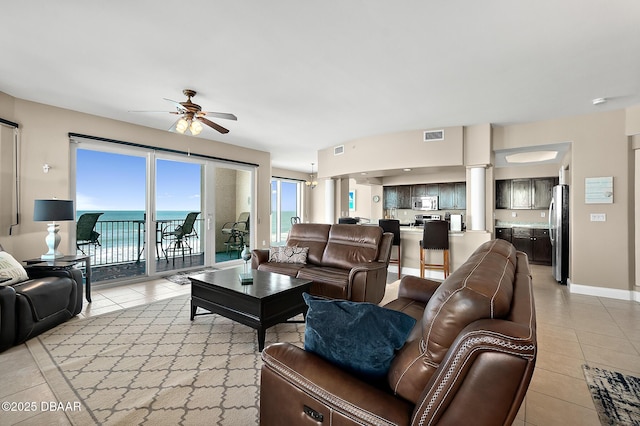 living room with ceiling fan, light tile patterned floors, and a water view